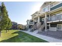 Exterior view of townhome with wooden stairs to covered entrance and a lawn at 543 Brennan Cir, Erie, CO 80516