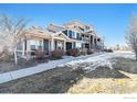 Exterior of townhome with covered entrance on a lawn with patches of melting snow at 543 Brennan Cir, Erie, CO 80516