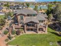 Expansive backyard with tiered deck, outdoor seating, hot tub, and lush lawn at 5763 Pelican Shores Dr, Longmont, CO 80504