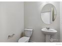 Bathroom featuring a pedestal sink, toilet, and round mirror at 1046 Scotts Peak Dr, Berthoud, CO 80513