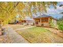 Lovely home with a brick facade, covered porch, and a lush front lawn adorned with autumn leaves at 109 E Iowa Ave, Berthoud, CO 80513