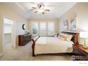 Cozy primary bedroom with neutral tones, tray ceilings, plush carpet, and natural light from shuttered windows at 13943 W 87Th Ln, Arvada, CO 80005