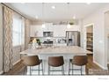 Bright kitchen with a large island, stainless steel appliances, and stylish pendant lighting and three chairs at 1923 Westport Ave, Berthoud, CO 80513