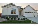 Charming white farmhouse-style home with a well-manicured lawn and a three car garage at 205 Cowbell Dr, Berthoud, CO 80513