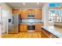 Well-lit kitchen features stainless steel appliances, wood cabinets, and hardwood flooring at 2238 Calais Dr # B, Longmont, CO 80504