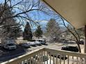 A balcony overlooking mature trees and vehicles parked in the community on a sunny day at 2800 Kalmia Ave # 320, Boulder, CO 80301