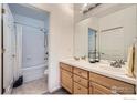 Well-lit bathroom featuring double sinks, vanity storage, tile floor, and bathtub with shower at 3575 Boulder Cir # 101, Broomfield, CO 80023