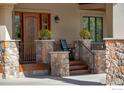 Charming front porch with stone pillars, wooden stairs, seating, and potted flowers that create an inviting entrance at 6425 Legend Ridge Trl, Niwot, CO 80503