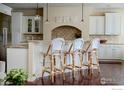 Bright kitchen with white cabinets, granite countertops, and three bar stools at 6425 Legend Ridge Trl, Niwot, CO 80503