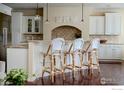 Bright kitchen featuring white cabinets, granite countertops, stainless steel appliances, pendant lights, and wicker bar stools at 6425 Legend Ridge Trl, Niwot, CO 80503