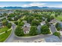 Wide aerial view of a suburban neighborhood near golf course, showcasing lush greenery and mountain views in the distance at 809 Saint Andrews Ln, Louisville, CO 80027