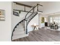 Bright entryway featuring a curved staircase with dark railing, light gray carpet, and view to dining area with hardwood floors at 809 Saint Andrews Ln, Louisville, CO 80027