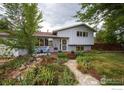 Charming home featuring a lush front yard, stone pathway, mature trees, and a welcoming deck at 1011 Vivian Cir, Boulder, CO 80303