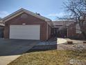 Inviting brick home with a spacious two-car garage and stone walkway to the front door at 1191 Twin Peaks Cir, Longmont, CO 80503