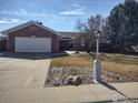 Classic brick home with a manicured lawn, mature trees, and a convenient two-car garage at 1191 Twin Peaks Cir, Longmont, CO 80503