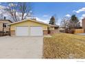 Inviting yellow home showcasing a two-car garage and well kept yard at 1614 Meeker Dr, Longmont, CO 80504