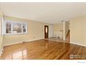 Spacious living room with gleaming hardwood floors and natural light from a large window at 1614 Meeker Dr, Longmont, CO 80504