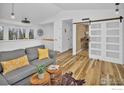 Open-concept living room with hardwood floors, barn door, and study nook at 1665 Bain Dr, Erie, CO 80516