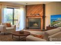 Cozy living room with a fireplace, wood accent wall, and sliding glass doors to a balcony at 2877 Shadow Creek Dr # 303, Boulder, CO 80303