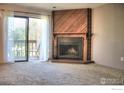 Cozy living room with a fireplace, wood accent wall, and sliding glass doors to a balcony at 2877 Shadow Creek Dr # 303, Boulder, CO 80303