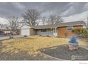 A single-story house with brick and gray siding featuring a two-car garage and a well-kept lawn at 313 Aspen Dr, Brighton, CO 80601