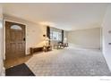 Spacious living room featuring neutral carpet, a decorative front door, and abundant natural light at 313 Aspen Dr, Brighton, CO 80601