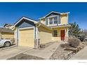 Charming two-story home with a yellow and blue exterior, a two-car garage, and a bright red front door at 400 Smith Cir, Erie, CO 80516