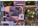 Birds eye view of the backyard featuring a manicured lawn, stone patio, outdoor fireplace, and privacy fencing at 405 Buckskin Rd, Berthoud, CO 80513