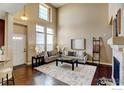 Living room with fireplace, soaring ceilings, neutral decor and hardwood flooring at 4742 Raven Run, Broomfield, CO 80023