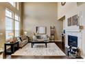 Inviting living room featuring soaring ceilings, a fireplace, and abundant natural light at 4742 Raven Run, Broomfield, CO 80023