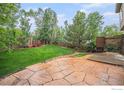 Expansive backyard featuring a stone patio, lush lawn, privacy fence and mature trees at 4910 Crimson Star Dr, Broomfield, CO 80023