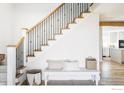 Bright entryway with hardwood floors, staircase with decorative iron spindles, bench seating, and light neutral decor at 4932 Valkyrie Dr, Boulder, CO 80301