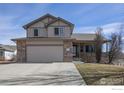 Inviting two-story home featuring a two-car garage and a quaint, covered front porch entry at 5288 Buttesfield St, Firestone, CO 80504