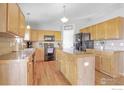 Spacious kitchen with wood cabinets, black appliances, center island, and hardwood floors at 5288 Buttesfield St, Firestone, CO 80504