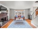 Bright living room featuring a brick fireplace, hardwood floors, and a large bay window at 5854 Urban Ct, Arvada, CO 80004