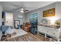 Cozy living room features a ceiling fan, dresser, rocker and bright natural light from a large window at 744 Grand Market Ave, Berthoud, CO 80513