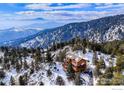 Aerial view of a gorgeous wood home nestled on a hillside surrounded by trees and snowy landscape at 84 Canon View Rd, Boulder, CO 80302