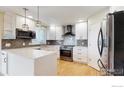 Modern kitchen with white cabinets, quartz countertops, and stainless steel appliances at 1875 Gordon Dr, Erie, CO 80516
