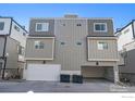 Rear view of a home showing the garage, gray siding, and an expansive driveway at 8500 W 62Nd Ave # D, Arvada, CO 80004