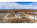 Aerial view of a rural property featuring a white house, barns, and vast fields under a cloudy sky at 14798 N 115Th St, Longmont, CO 80504