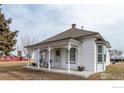 Charming white home with a cozy front porch featuring decorative columns, seating, and a well-maintained landscape at 14798 N 115Th St, Longmont, CO 80504