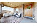 Inviting covered front porch with cozy seating, stone accents, and a welcoming entrance at 15955 Humboldt Peak Dr, Broomfield, CO 80023