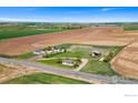 Expansive aerial view of a rural property featuring multiple homes and agricultural fields under a clear blue sky at 19858 County Road 1, Berthoud, CO 80513