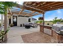 Charming outdoor kitchen and living area with a built-in grill and comfortable seating under a pergola at 19858 County Road 1, Berthoud, CO 80513