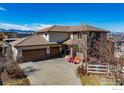 Aerial view of a home with stone accents, a three-car garage, and mountain views in the background at 2005 Calico Ct, Longmont, CO 80503