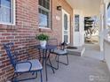 Inviting front porch area with a cozy seating arrangement and charming brick accents near the entrance at 2111 Pintail Dr, Longmont, CO 80504