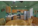 Bright kitchen with wood cabinets and stainless steel appliances, adjacent to a dining area at 2218 E 109Th Dr, Northglenn, CO 80233