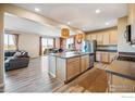 Open kitchen featuring a large island, stainless steel appliances, and wood-look floors at 376 Country Rd, Berthoud, CO 80513