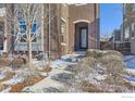 Close up view of a brick townhome, featuring a front door entrance and landscaped front yard at 5390 Valentia St, Denver, CO 80238