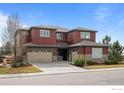 Attractive two-story home with a three-car garage, well-kept lawn, and complementary stone and red design at 626 Trails At Coal Creek Dr, Lafayette, CO 80026